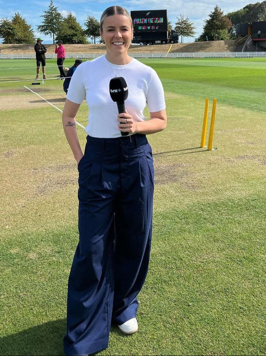 A close-up of a woman's navy wide-leg pants with double pleats, showing the fabric and design details.