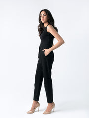 A close-up of a woman's hand placing into a front pocket of black high-waisted fitted pants.