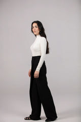 Woman wearing a white top and black wide-leg pants on a gray background