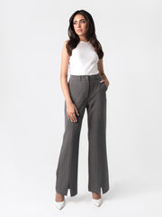 A woman in a white top and dark grey flared pants with front slits, fitted waist belt, and cross pockets.