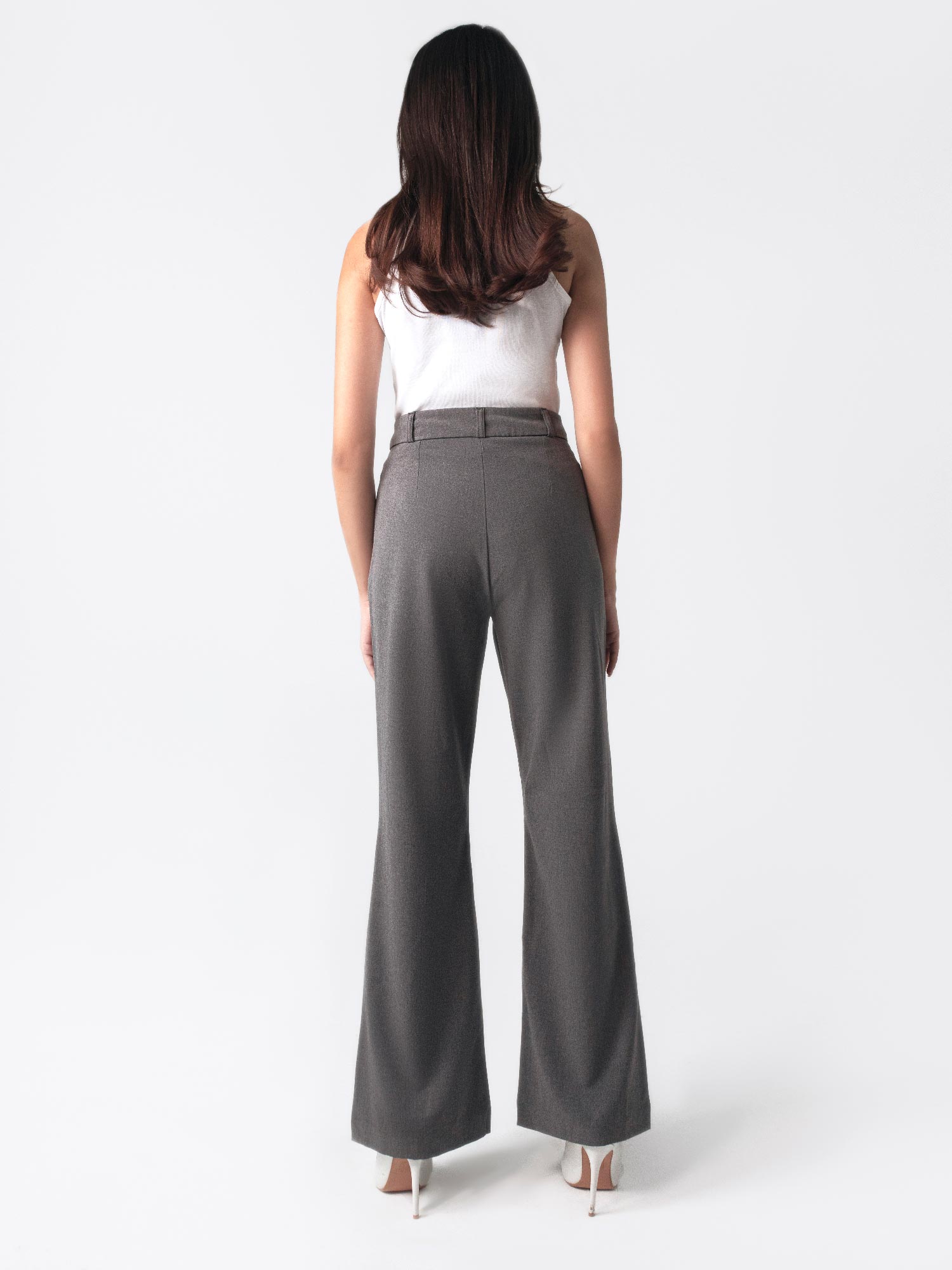 A woman in a white top and dark grey flared pants with front slits, fitted waist belt, and cross pockets.