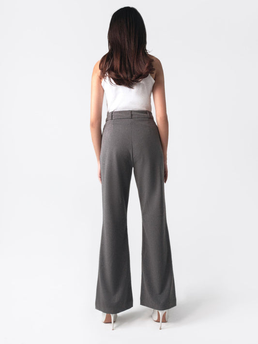A woman in a white top and dark grey flared pants with front slits, fitted waist belt, and cross pockets.