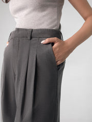 Low-rise black wide leg pants with a fitted belt, pleats, and multiple pockets, designed for a formal and smart look.