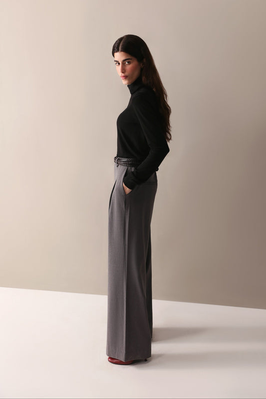 A woman in a black top and low-rise grey wide leg pants with pleats and pockets, showcasing a smart, flattering fit.
