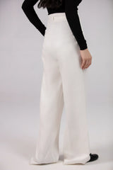 Person wearing white wide-leg pants and a black top on a plain background