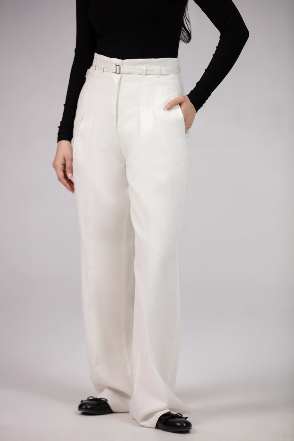 Person wearing white pants and a black top on a plain background