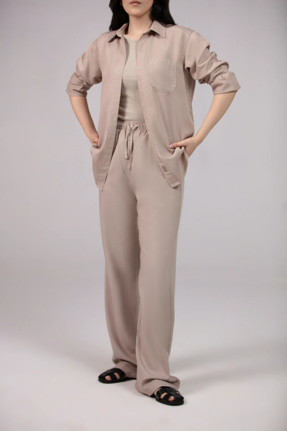 Person wearing a beige jumpsuit on a plain background