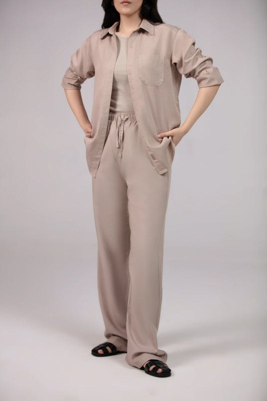 Person wearing a beige jumpsuit on a plain background