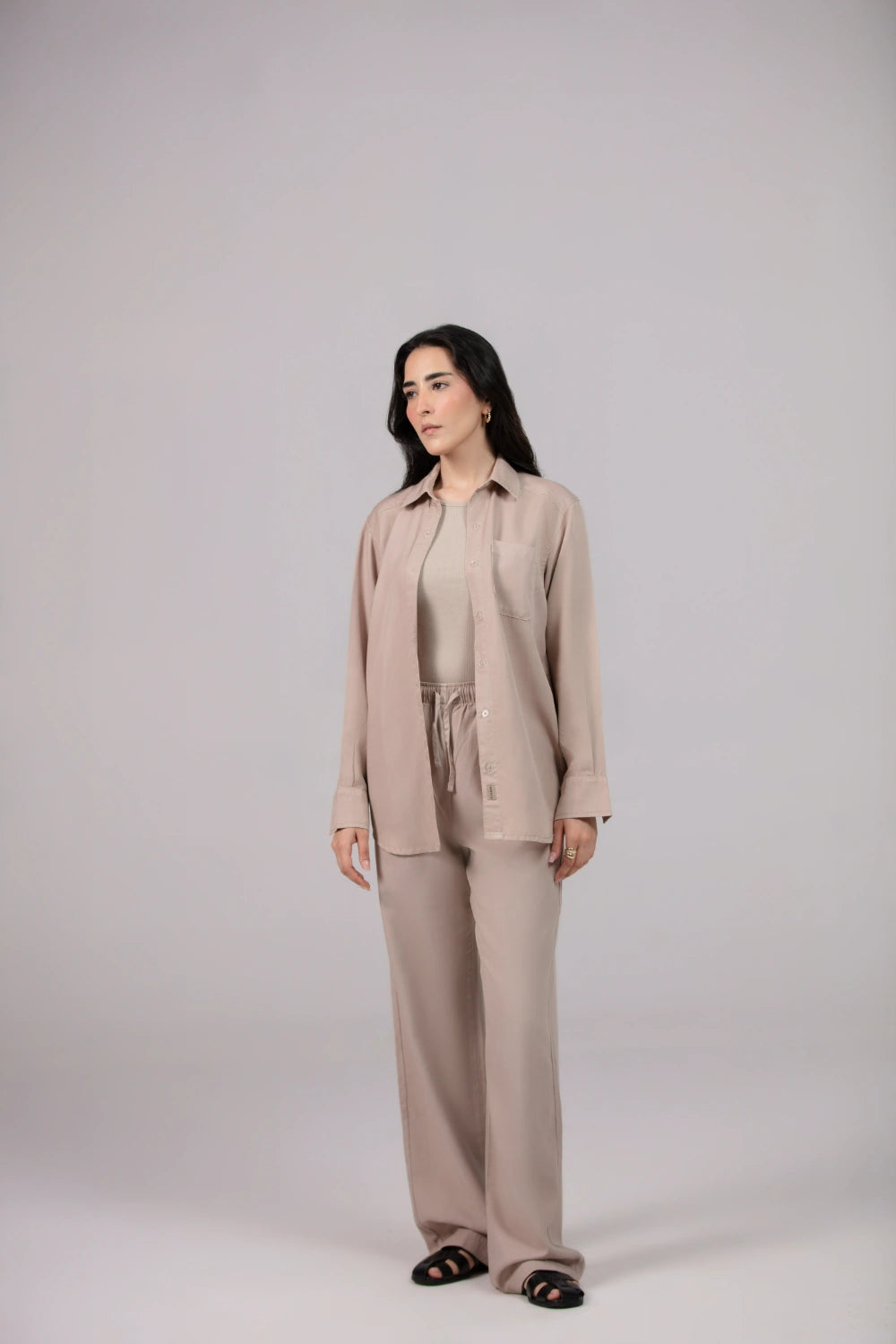 Woman wearing a beige suit standing against a plain background