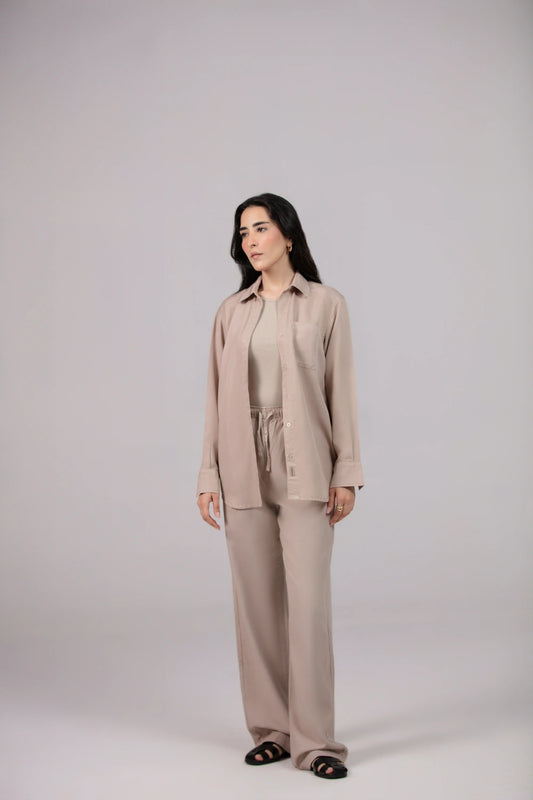 Woman wearing a beige suit standing against a plain background