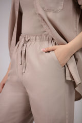 Person wearing a beige outfit with a drawstring waist and a plain background