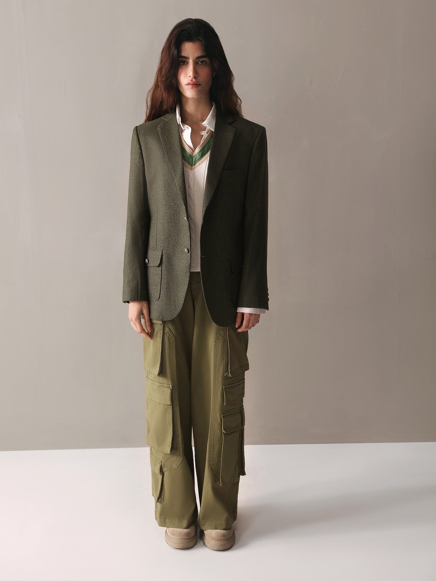 A woman wearing olive green cargo pants paired with a white sweater, presenting a relaxed and fashionable outfit.