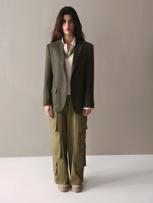 A woman wearing olive green cargo pants paired with a white sweater, presenting a relaxed and fashionable outfit.