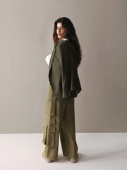  A woman dressed in olive green cargo pants and a white sweater stands confidently, showcasing a casual yet stylish look.
