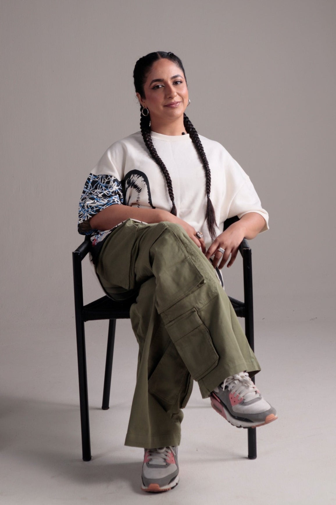 Person wearing a white shirt, green pants, and patterned shoes on a plain background