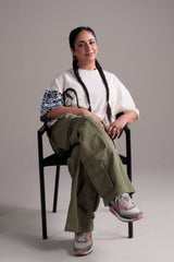 Person wearing a white shirt, green pants, and patterned shoes on a plain background