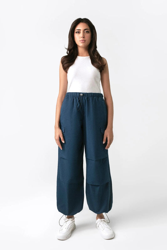A woman standing and facing to the side, wearing navy blue wide leg cargo pants with an elasticated waistband and drawcord details.