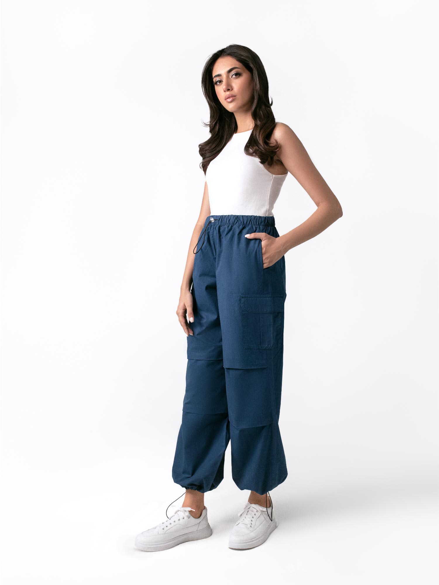 A woman standing and facing to the side, wearing navy blue wide leg cargo pants with an elasticated waistband and drawcord details.