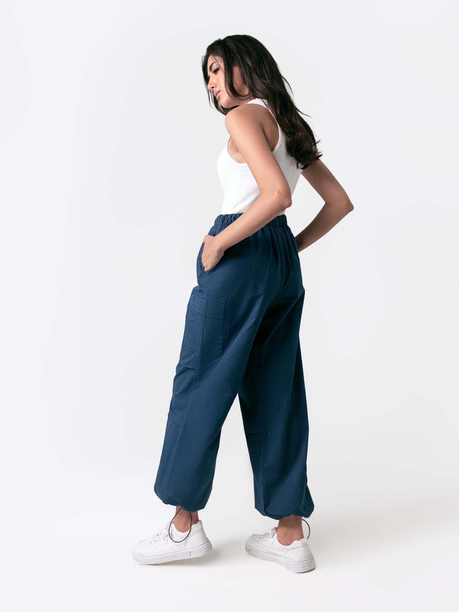 A woman standing and facing to the side, wearing navy blue wide leg cargo pants with an elasticated waistband and drawcord details.