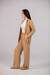 Woman wearing a beige cardigan and pants on a plain background