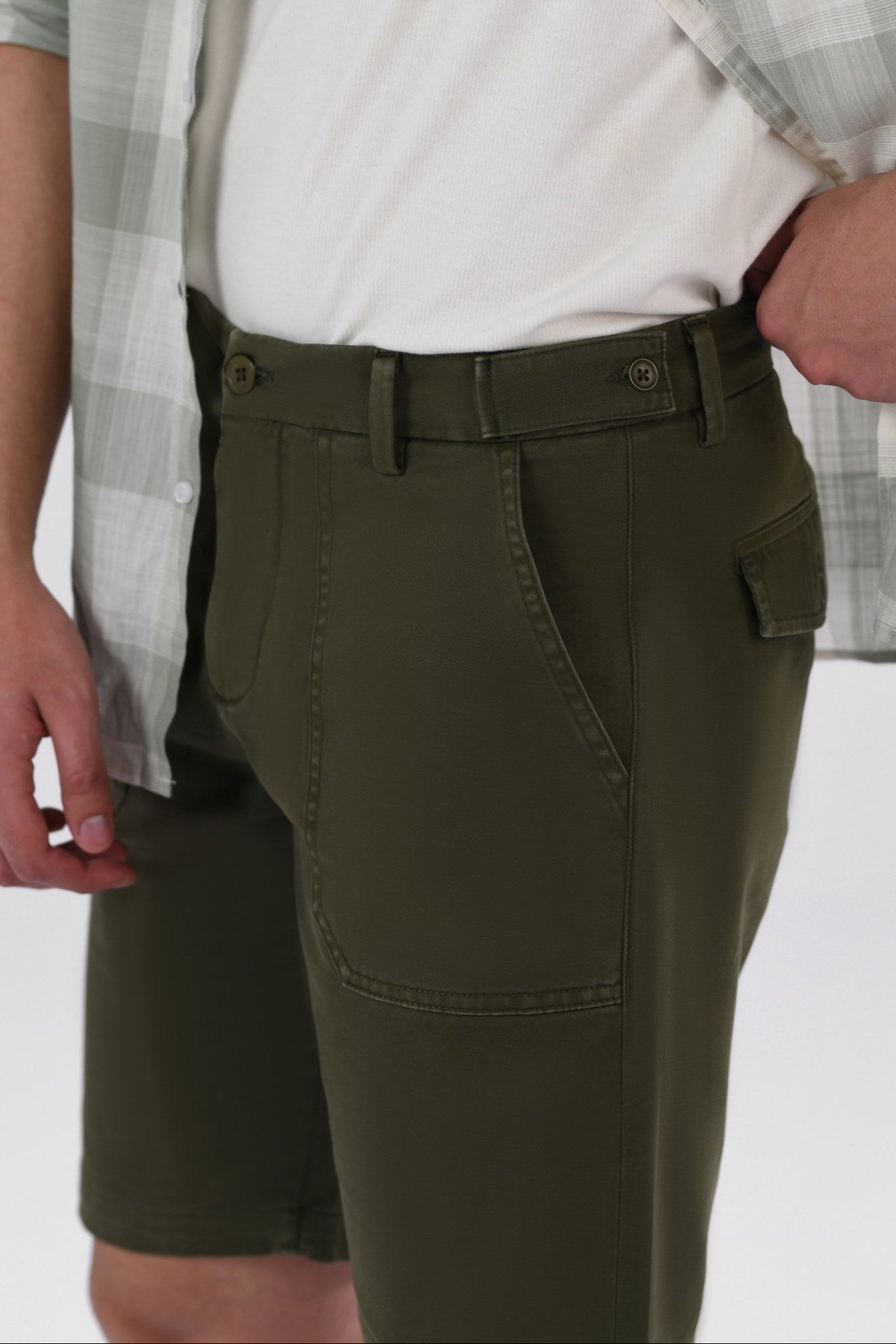 A pair of olive green safari shorts for men with a non-functional belt strap, classic patch pockets, and a zip fly opening.