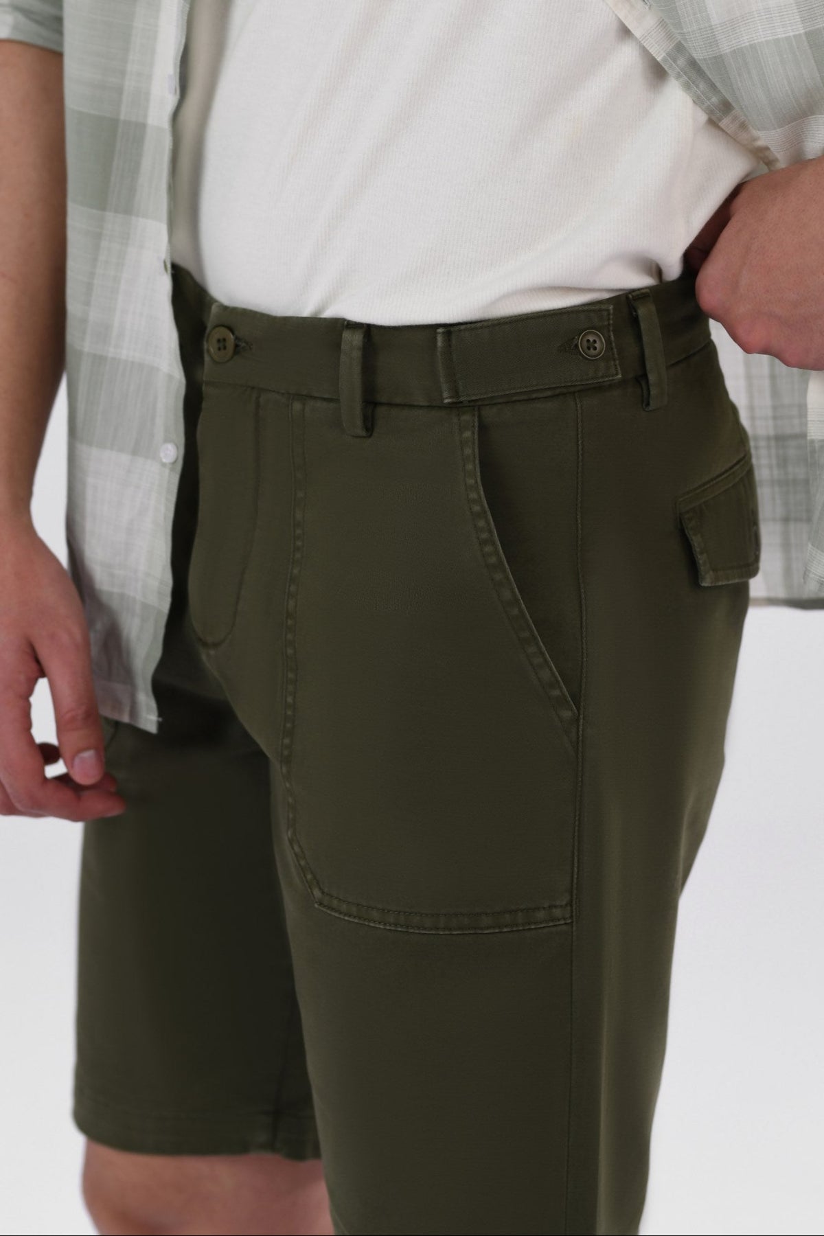 A pair of olive green safari shorts for men with a non-functional belt strap, classic patch pockets, and a zip fly opening.