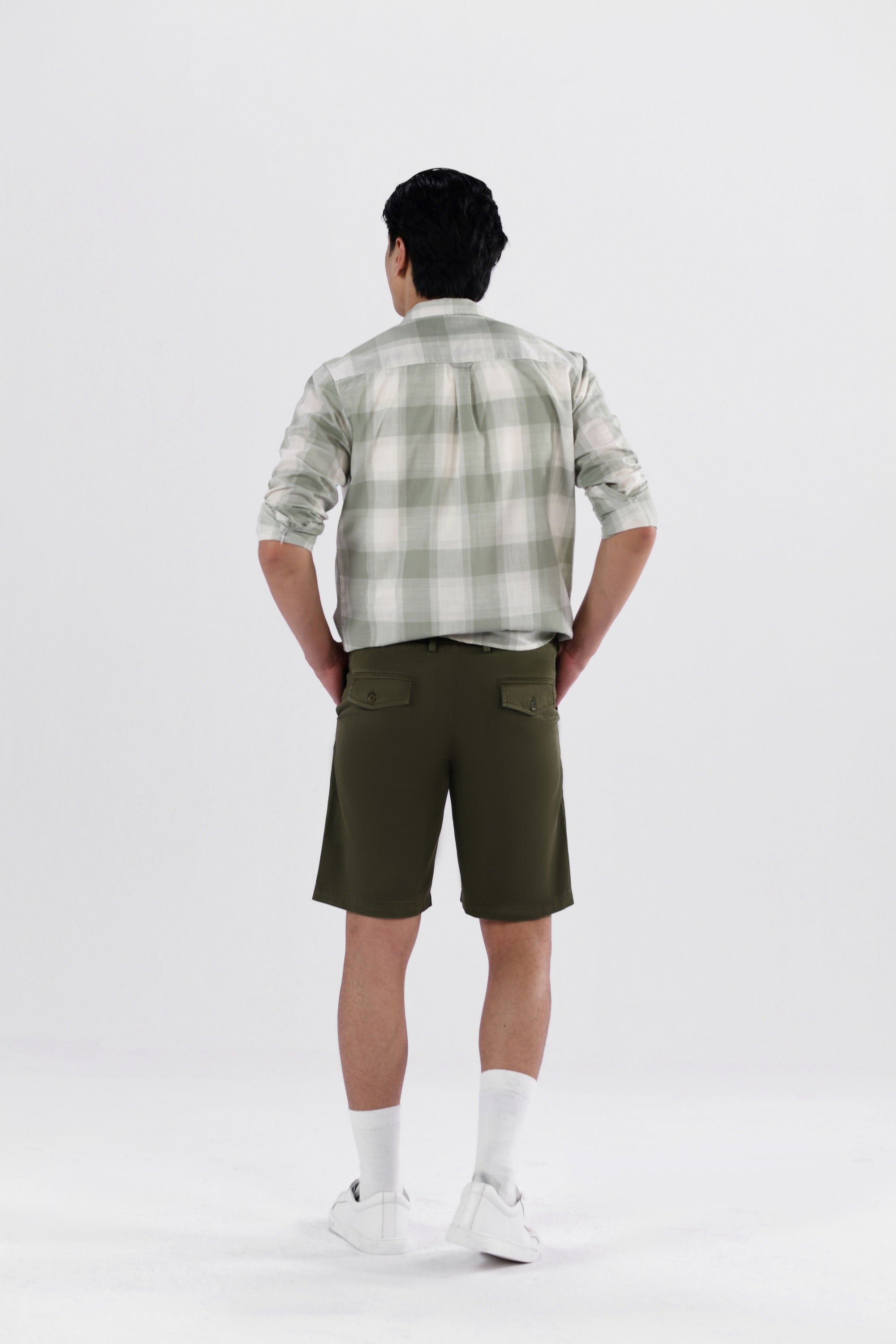 A pair of olive green safari shorts for men with a non-functional belt strap, classic patch pockets, and a zip fly opening.