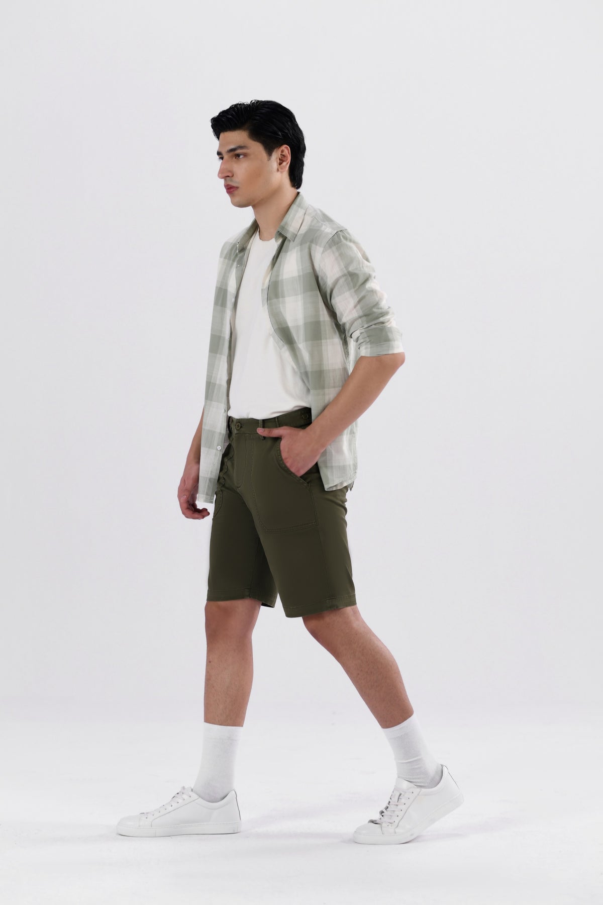 A pair of olive green safari shorts for men with a non-functional belt strap, classic patch pockets, and a zip fly opening.