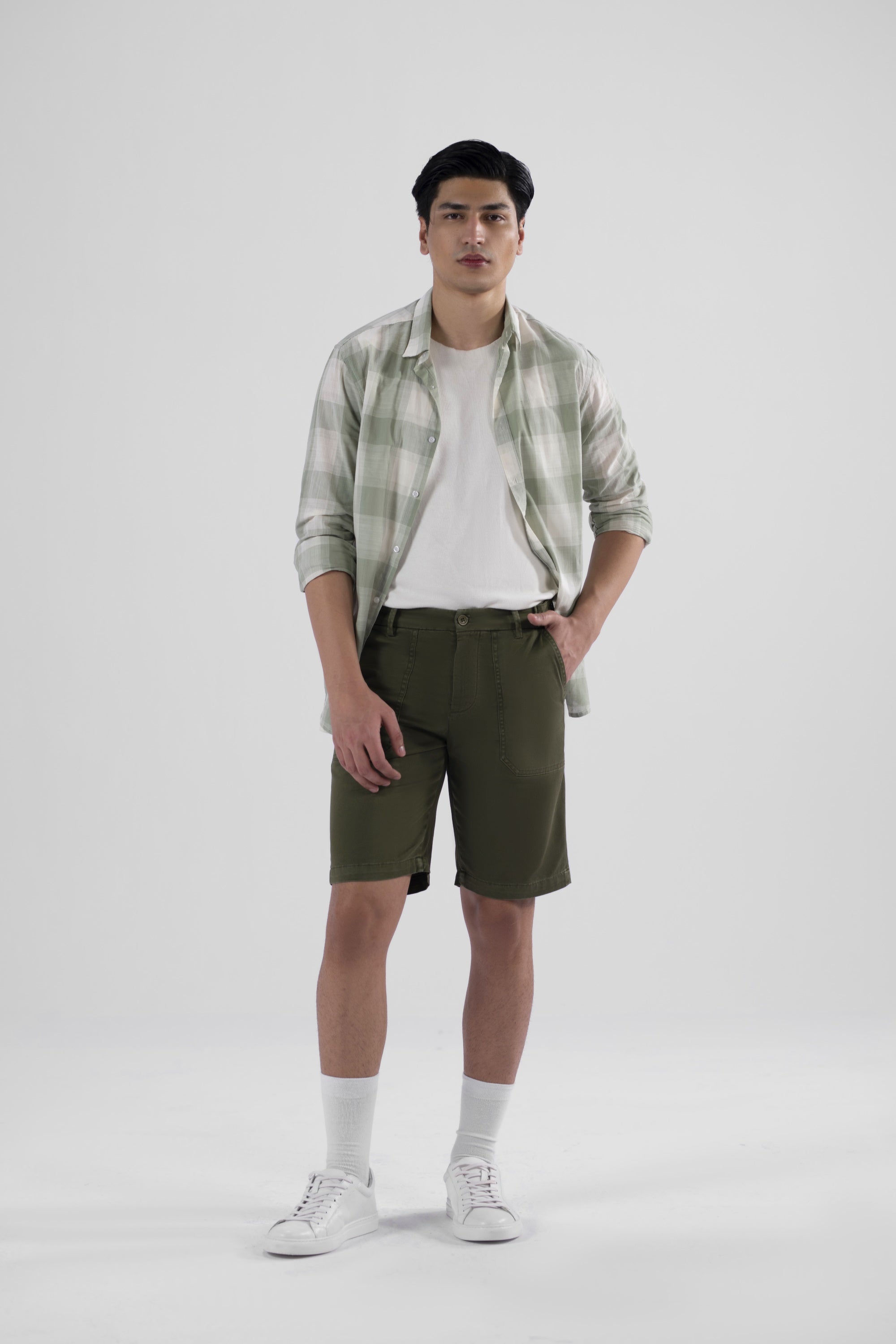 A pair of olive green safari shorts for men with a non-functional belt strap, classic patch pockets, and a zip fly opening.