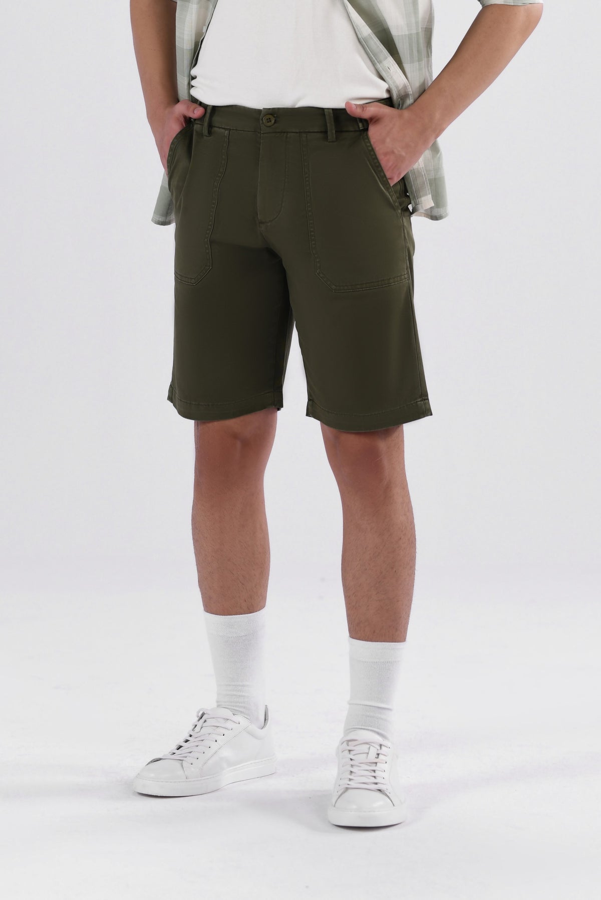 A pair of olive green safari shorts for men with a non-functional belt strap, classic patch pockets, and a zip fly opening.