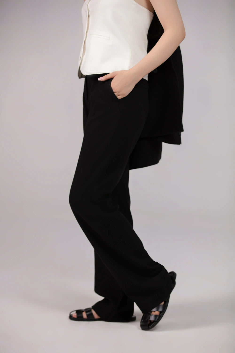Person wearing a white top and black wide-leg pants on a plain background
