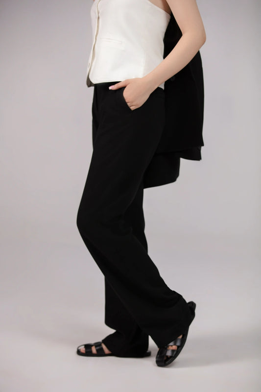 Person wearing a white top and black wide-leg pants on a plain background