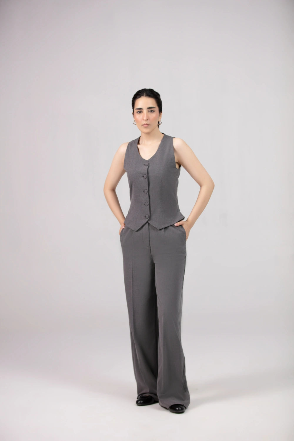 Woman wearing a gray vest and pants set on a white background