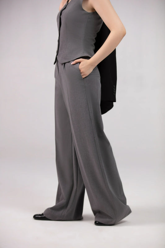 Person wearing a gray outfit with wide-leg pants on a plain background