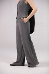 Person wearing a gray outfit with wide-leg pants on a plain background