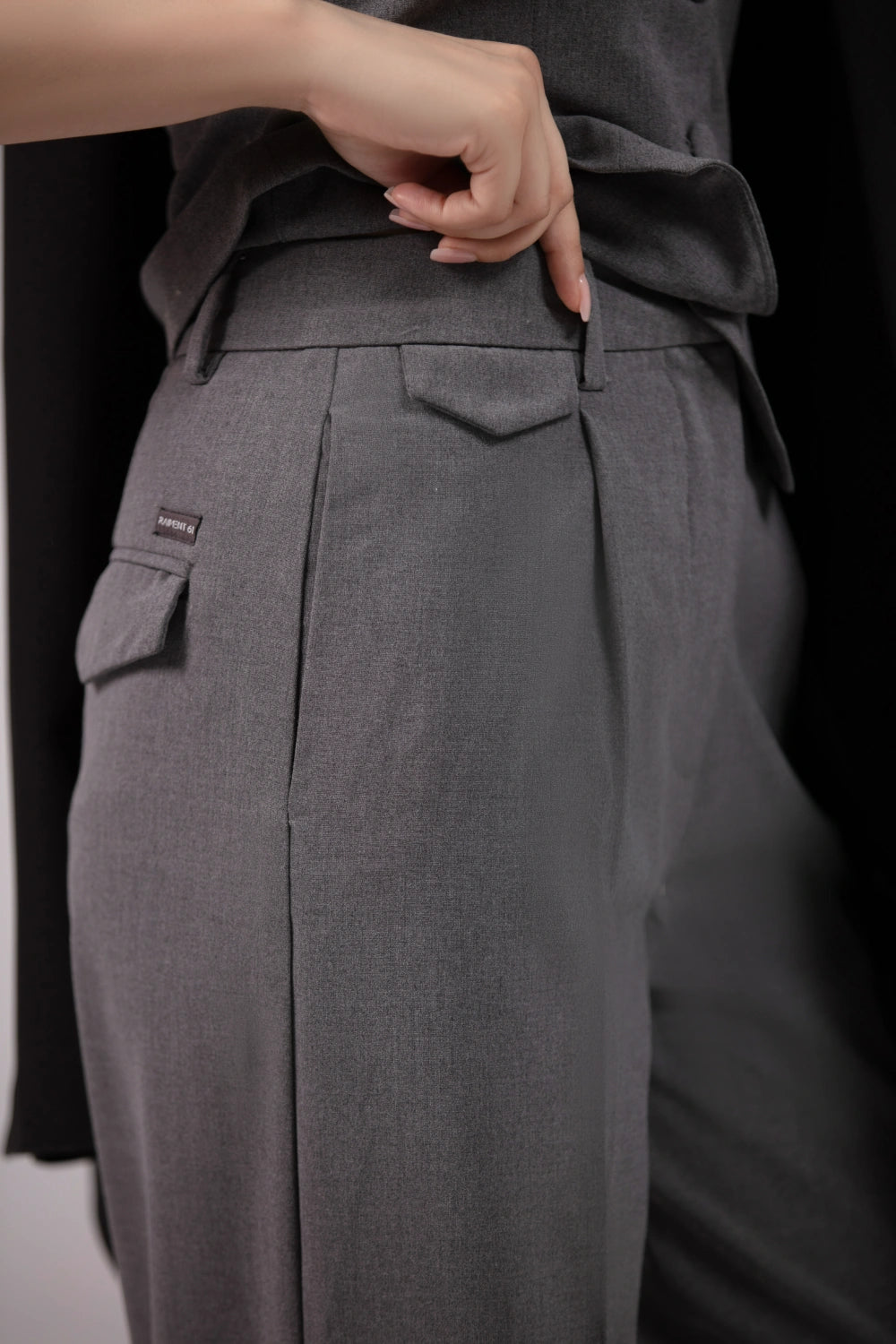 Gray pants with a belt and pocket detail on a black background