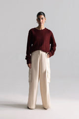 Person wearing a burgundy sweater and beige pants on a light gray background