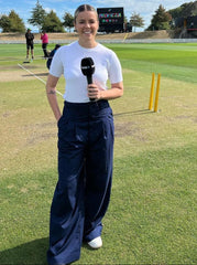 A close-up of a woman's navy wide-leg pants with double pleats, showing the fabric and design details.