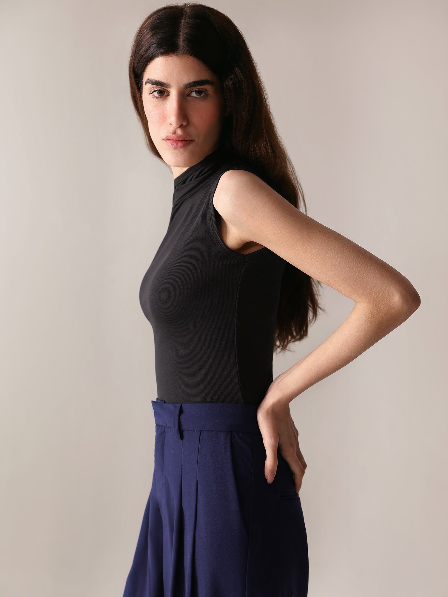 A close-up of a woman's navy wide-leg pants with double pleats, showing the fabric and design details.