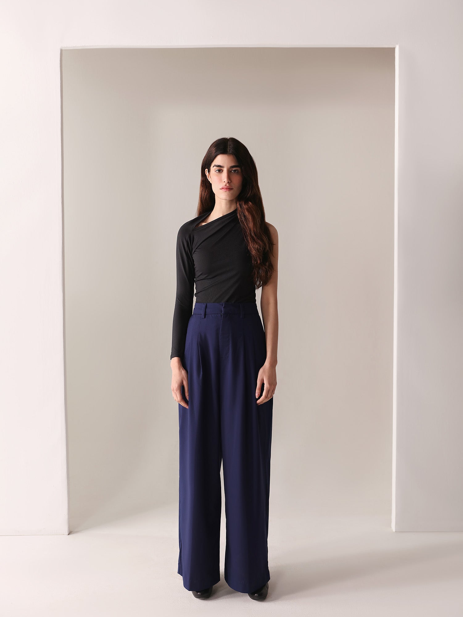 A close-up of a woman's navy wide-leg pants with double pleats, showing the fabric and design details.