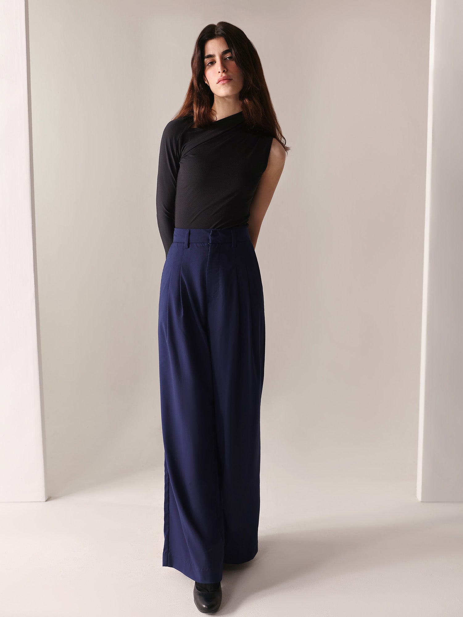 A close-up of a woman's navy wide-leg pants with double pleats, showing the fabric and design details.
