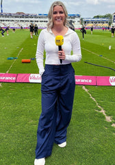 A close-up of a woman's navy wide-leg pants with double pleats, showing the fabric and design details.