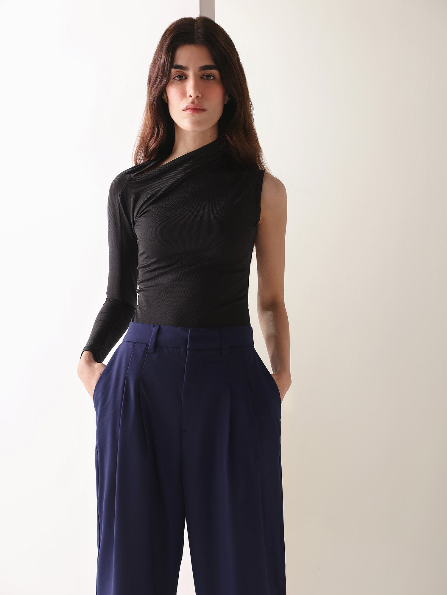 A close-up of a woman's navy wide-leg pants with double pleats, showing the fabric and design details.
