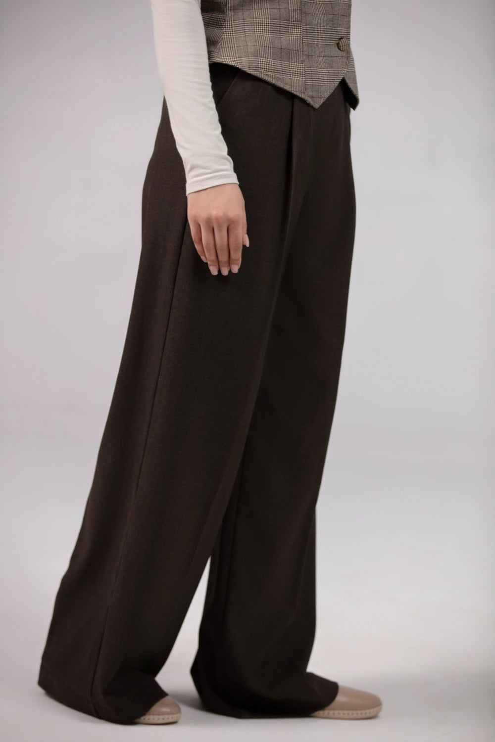 Person wearing wide-leg brown pants on a plain background