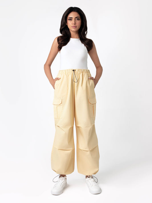 A person wearing yellow wide leg cargo pants with an elasticated waistband and side cargo pockets.