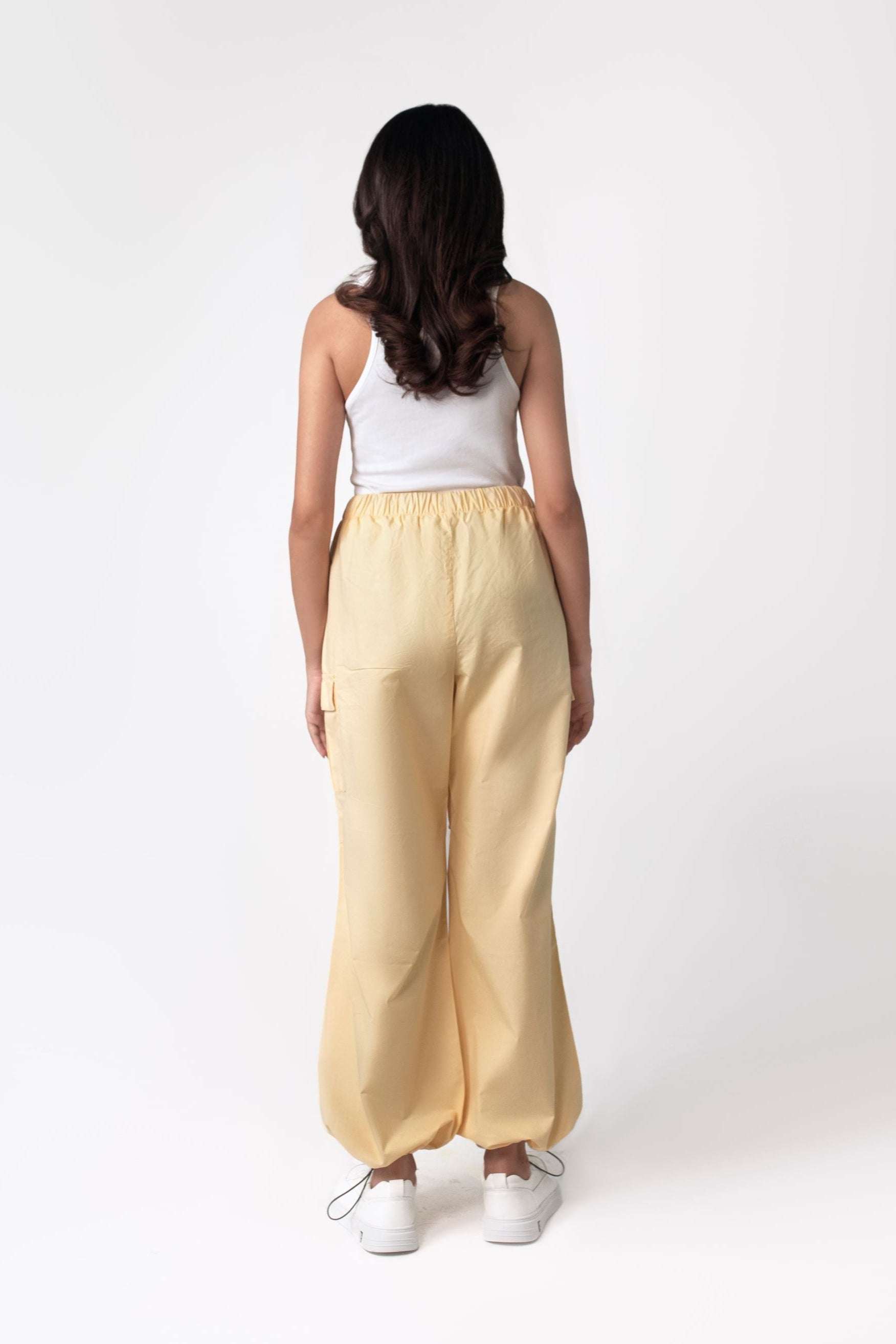 A person wearing yellow wide leg cargo pants with an elasticated waistband and side cargo pockets.