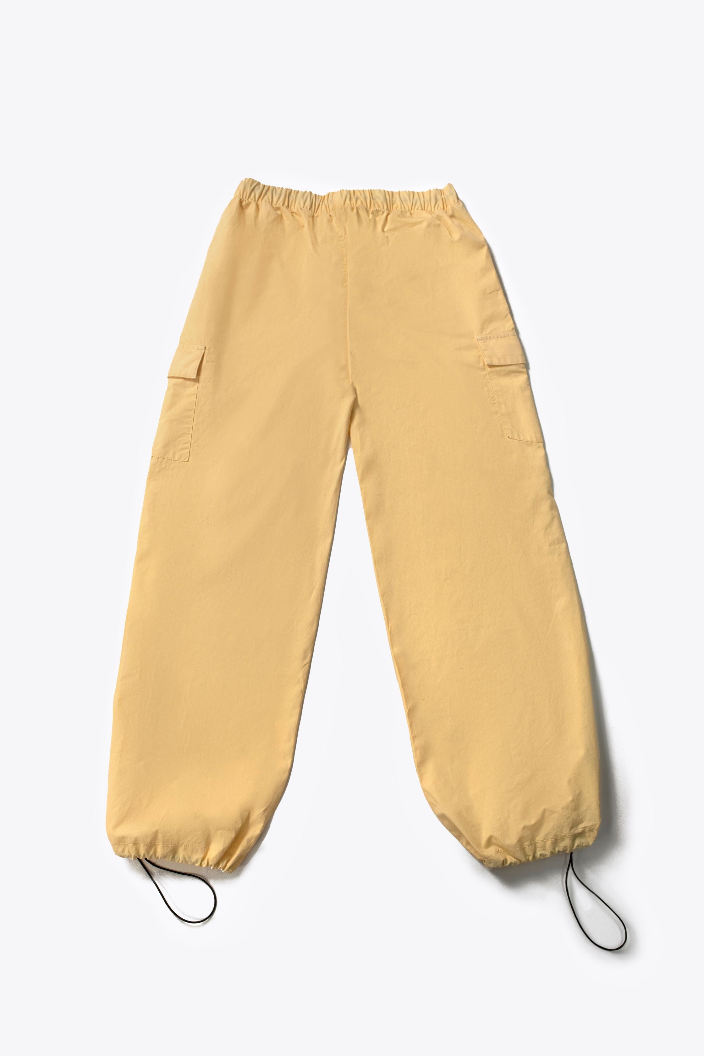 A person wearing yellow wide leg cargo pants with an elasticated waistband and side cargo pockets.
