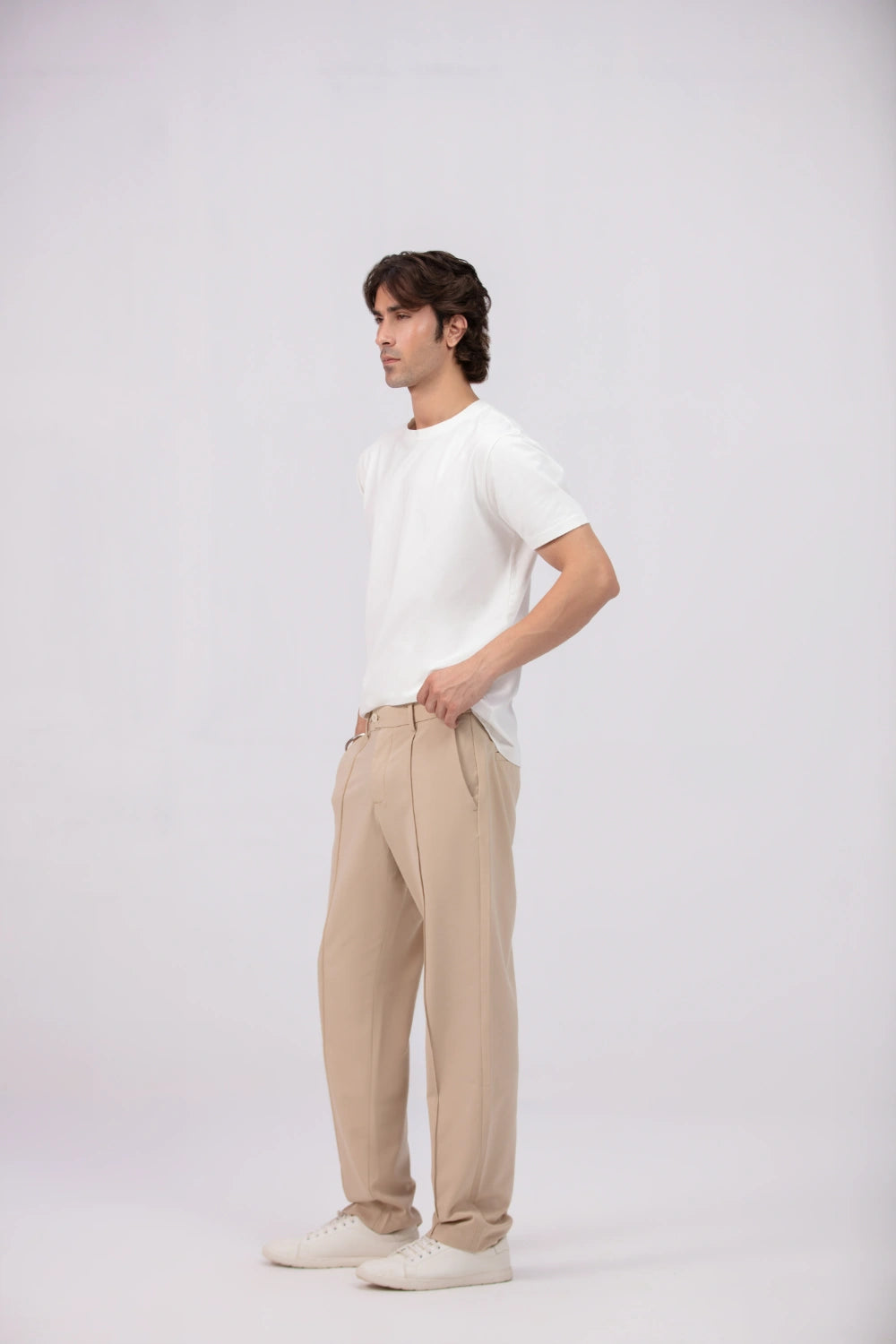Man wearing a white t-shirt and beige pants on a white background