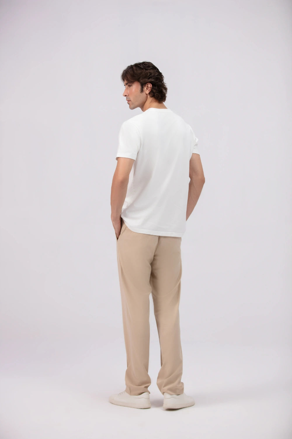 Man wearing a white t-shirt and beige pants on a white background